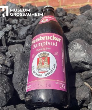 Eine Flasche des Hersbrucker Dampfbiers liegt auf den Kohlen, die zum Befeuern der Dampfmaschinen benutzt wird. 